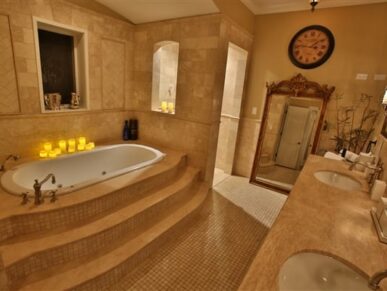 jacuzzi tub with steps leading up, 2 vanity sinks, large mirror