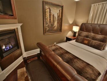 bedroom with corner fireplace and tv above